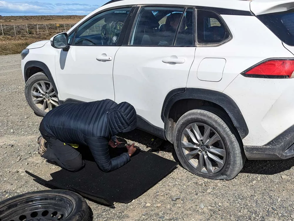 Adrian changing a flat tyre on a white SUV