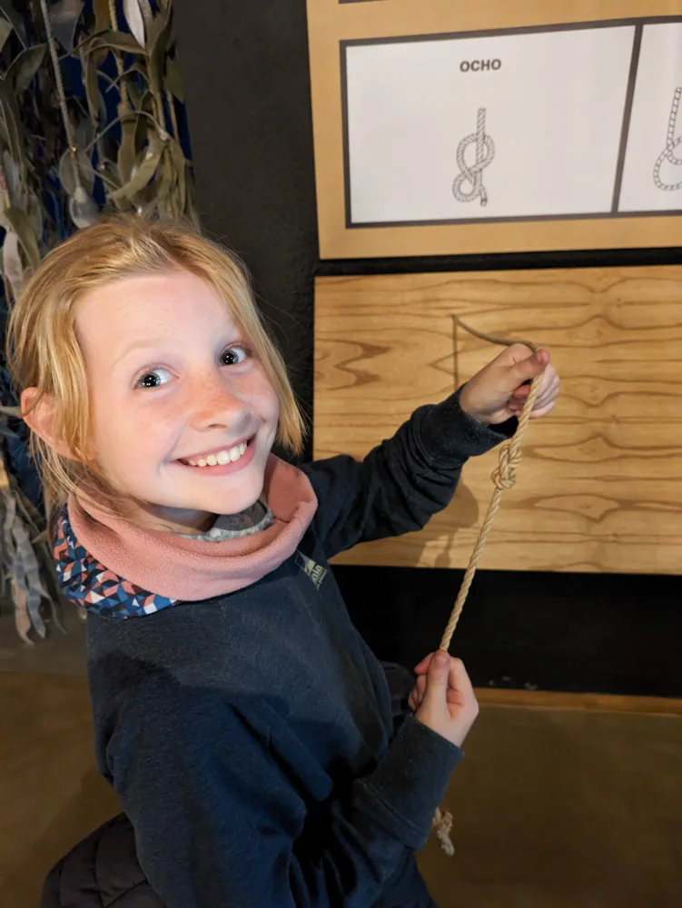 A happy Georgia showing off her 'ocho knot' tying skills with a diagram of the knot in the background.