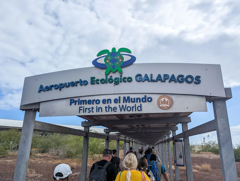 Passengers walking under the 'First in the World', Galapagos ecological airport sign after disembarking from their flight.