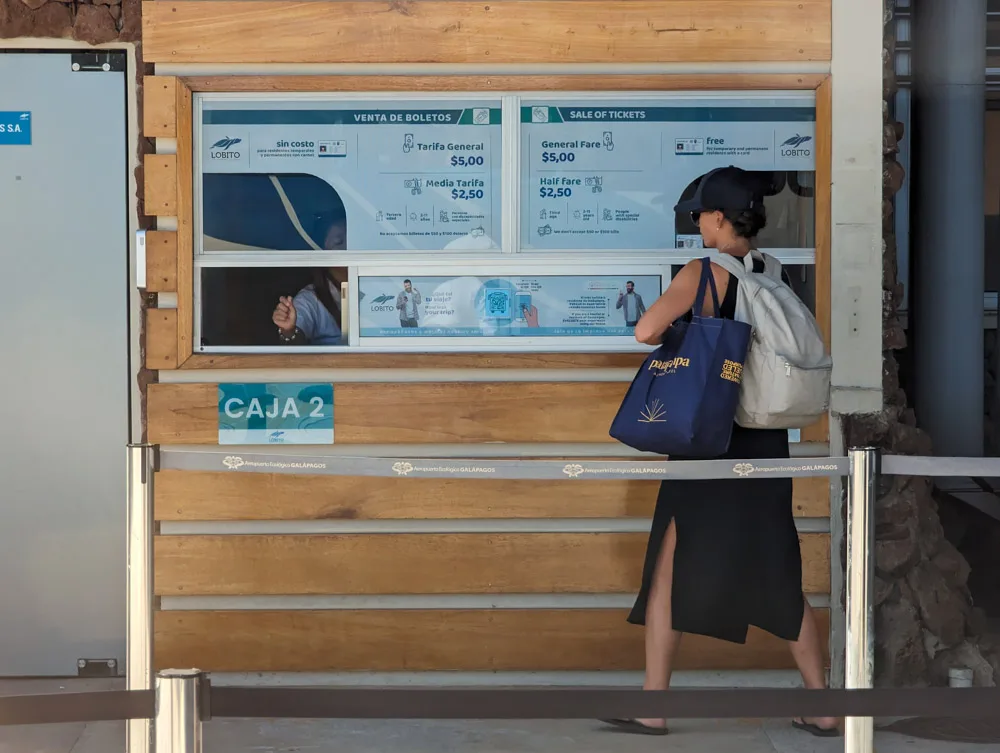 A lady standing at the bus ticket office at Baltra Airport on the Galapagos Islands getting her ticket.
