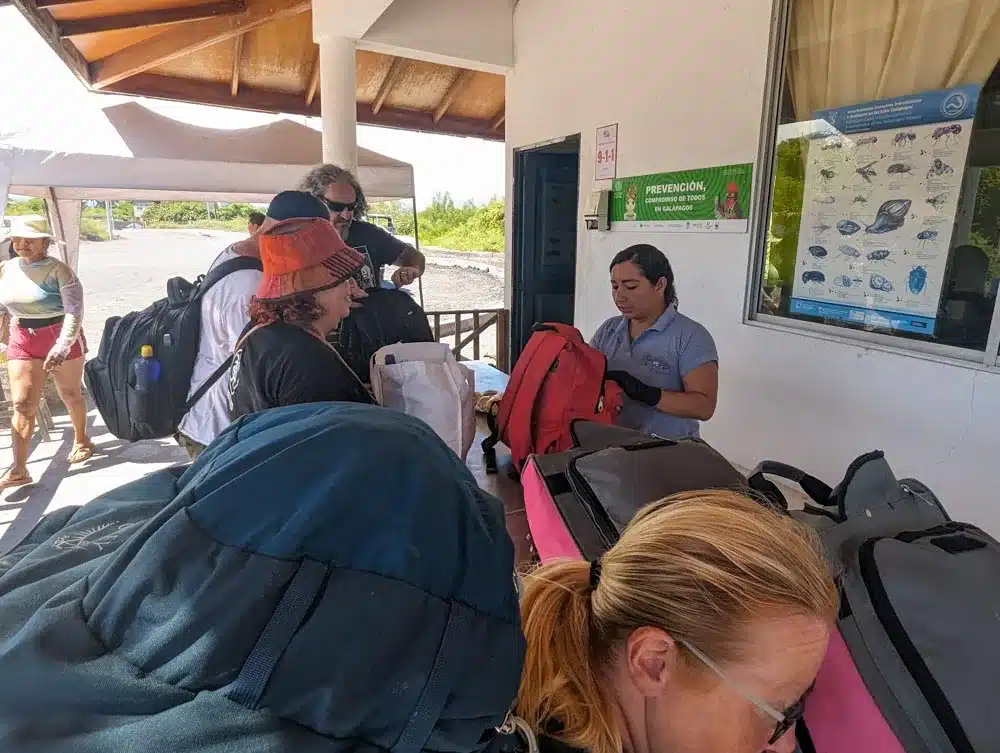 A lady checking passenger bags at the ferry boarding point on Isla Isabella with a queue of people waiting.