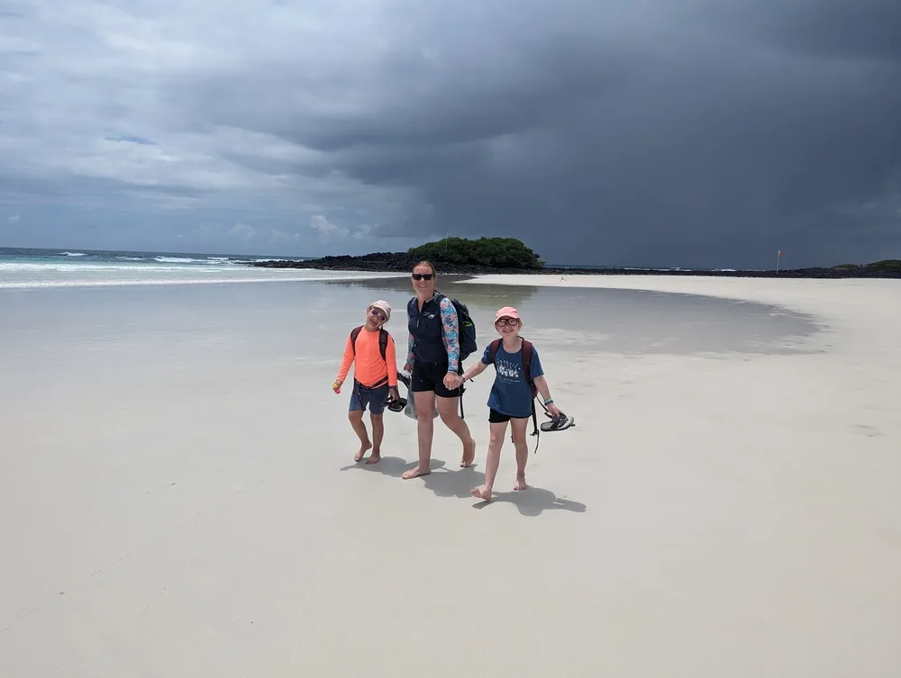 Exploring Tortuga Bay Galapagos with kids. Kirsty and the girls walking across the white sand beaches with the sea in the distance.